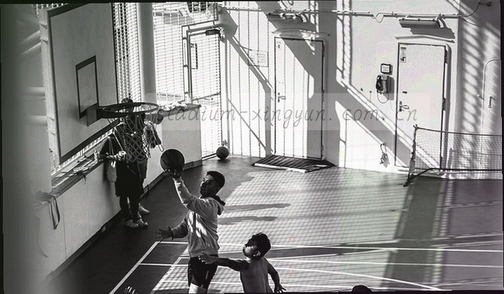 球场俯拍一角，中圈与边线构成对角线，靛蓝色调下暖橙线条醒目